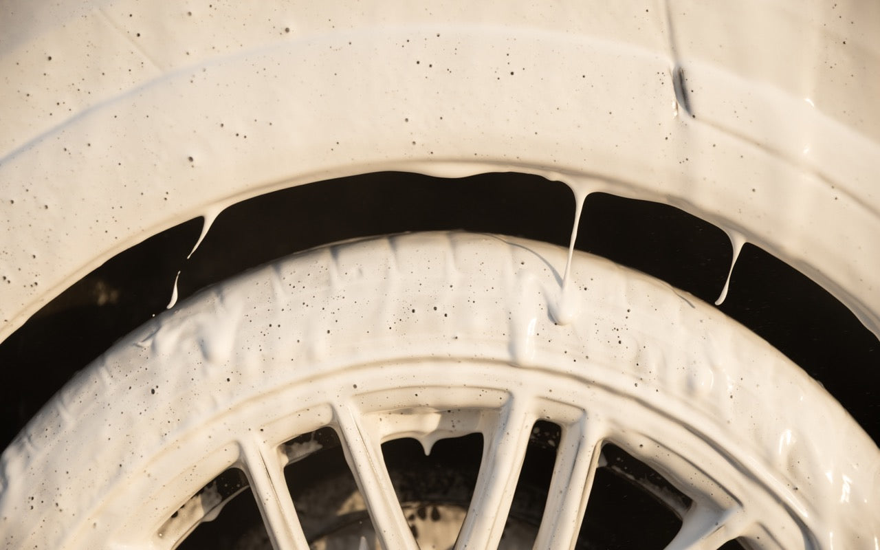 Thick foam covering a car wheel and tyre during a pre-wash