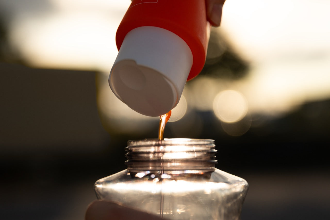 Grime Time car pre-wash concentrate being poured into a clear mixing bottle