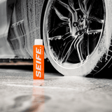 Grime Time car pre-wash bottle beside a foam-covered alloy wheel
