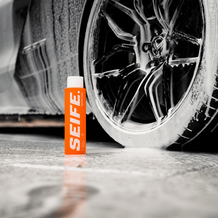 Grime Time car pre-wash bottle beside a foam-covered alloy wheel