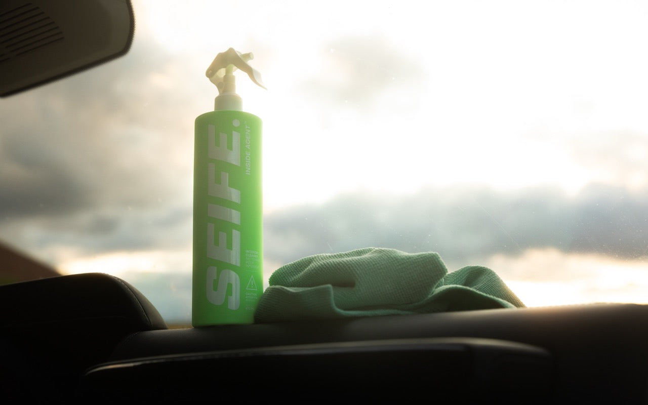 Inside Agent interior cleaner and a microfibre towel on a car dashboard