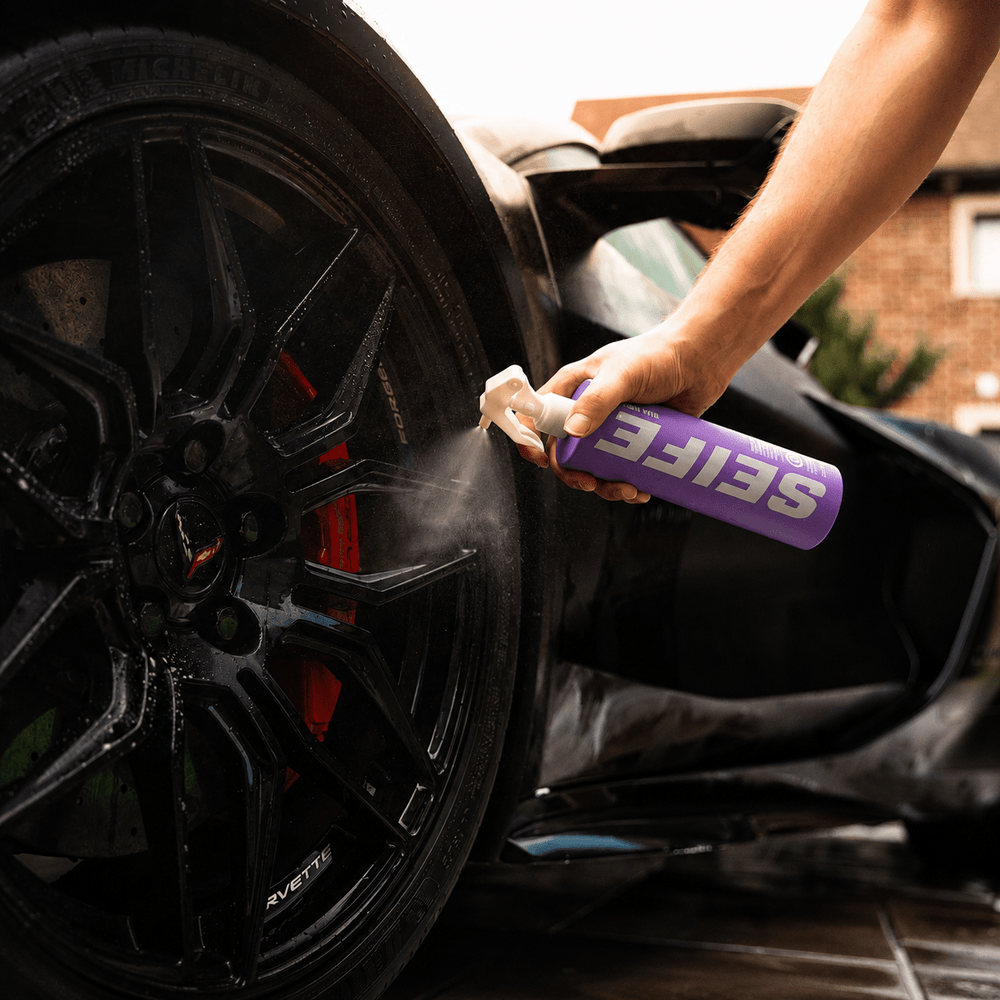 Rim Revive wheel cleaner being sprayed onto a wet black alloy wheel with red brake calipers